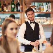 Cropped shot of a handsome young waiter smiling while standing in a bar.